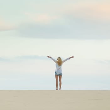 Relaxed woman enjoying freedom feeling happy at beach at dusk. Serene relaxing woman in pure happiness and elated enjoyment with arms raised outstretched up.