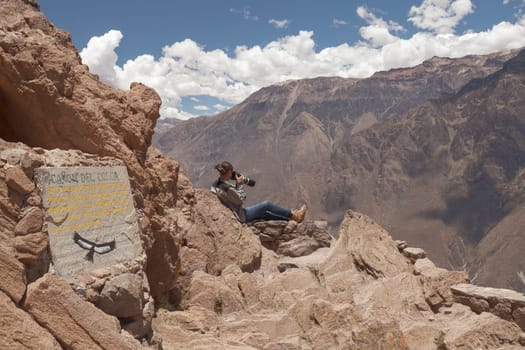 Young woman photographing condors in Colca, Arequipa, Peru.