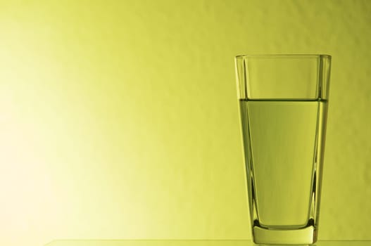 Still life illuminated with lemonade glass on glass plate yellow.