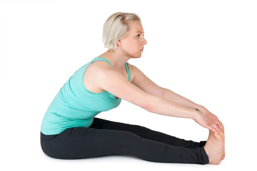 Full body view of a young blonde woman in yoga exercise "floor seat hands on her feet"" on white background with light shadows"