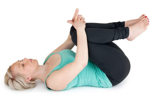 Full body view of a young blonde woman during yoga exercise "in supine position to cover the knees"" against a white background with light shadow"