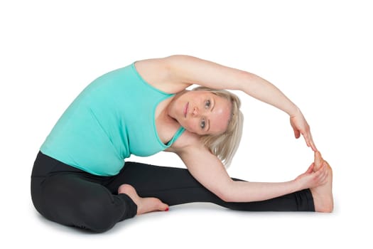 Full body view of a young blonde woman during yoga exercise "sit i half leg and the upper body stretched to the left foot"" against a white background with a slight shadow"