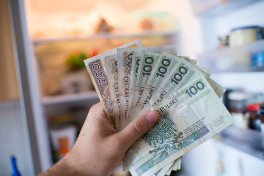 hand with pln money in the front of the open fridge