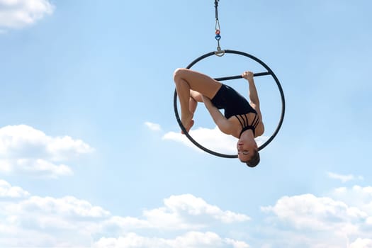 Sport woman doing exercises with a hoop, outdoor, against the blue sky. Sports equipment and lifestyle concept. Antigravity yoga.