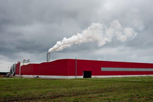 Smoking industrial pipes. red shed with a chimney and smoke
