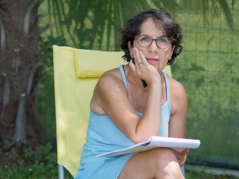 a mature woman writes a letter in the garden