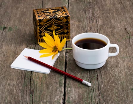 pencil, coffee and the casket decorated with a yellow flower, a subject flowers and drinks, seasons spring and summer
