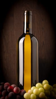 Bottle of white wine with grapes on a dark wooden background