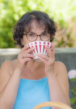 a mature woman with glasses drinking a cup of tea
