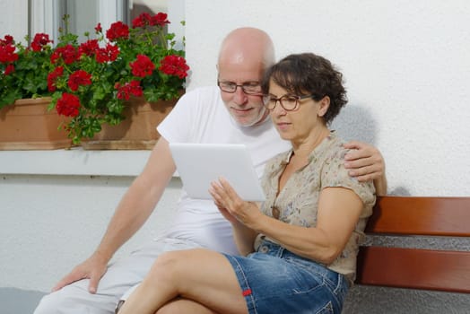 a senior couple with a tablet, outside