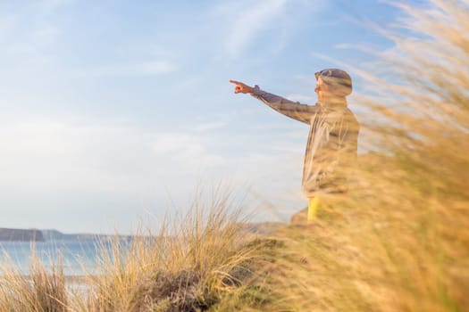 Sporty active man pointing hand on horizon, enjoying beauty of nature, freedom and life at beautiful landscape. Active lifestyle outdoors.