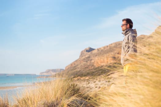 Sporty active man looking at distance, enjoying beautiful nature, freedom and life at serene landscape at Balos beach. Active lifestyle outdoors.
