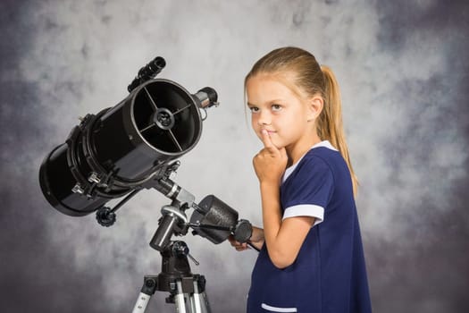 Seven-year girl looks at the sky while standing at the telescope
