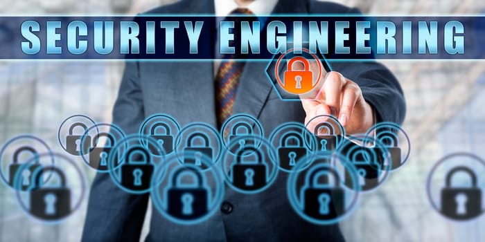 Torso of manager in steel blue business suit is touching SECURITY ENGINEERING on a transparent interface. Business metaphor and information technology concept for crime prevention and cryptography.