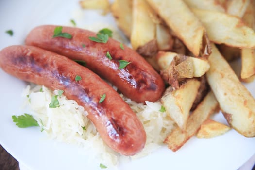Two sausages on sauerkraut with a side of french fries