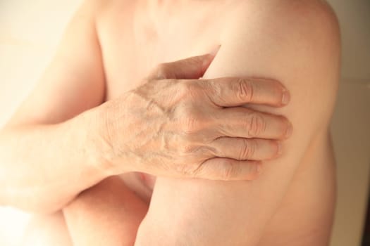 An older man with his hand on an aching arm muscle.