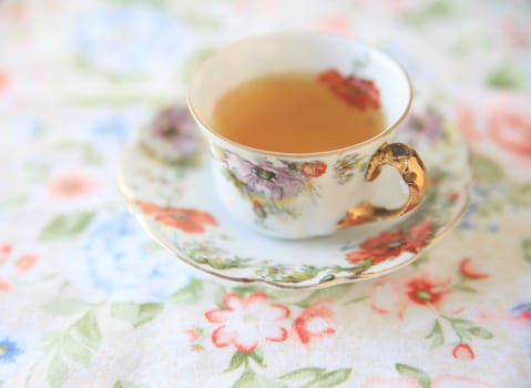 Floral cup with tea on a flowery cloth