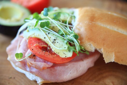 Sandwich of ham, tomato, avocado and sprouts with black pepper