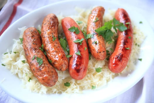 Several sausages on a bed of sauerkraut with fresh cilantro