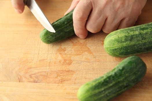 A man slices pickling cucumbers on a cutting board with copy space.