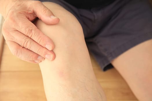 Older man puts a hand on his sore knee joint.