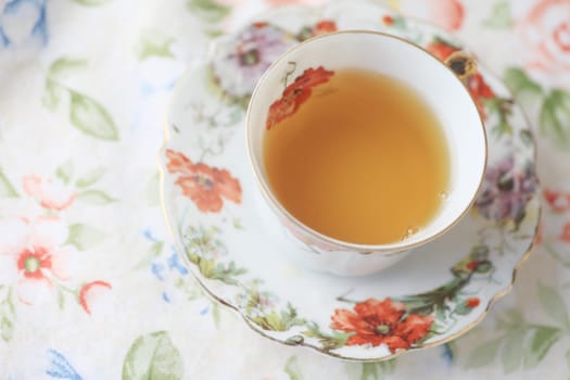 Cup of tea in floral cup on flower print cloth