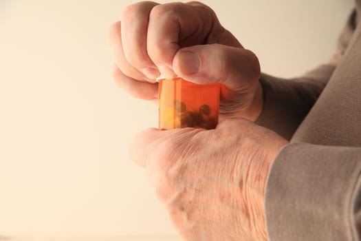 A senior man struggles to open his prescription capsules.