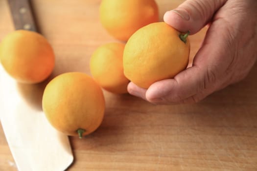 Several lemons on a cutting board, a man holding one