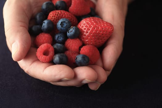 Fresh berries in a man's hands on a black background