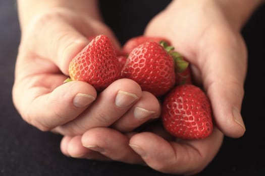 A man holds fresh strawberries in both hands.