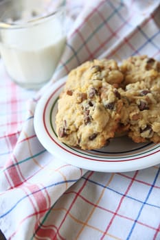 Chocolate and butterscotch chip cookies on a colorful dish with glass of milk on multi-colored dish cloth