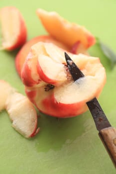Closeup of a knife cutting into a juicy white peach