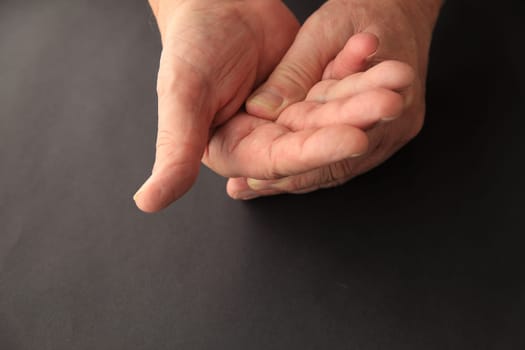 A senior man applies light pressure to the palm of his hand.