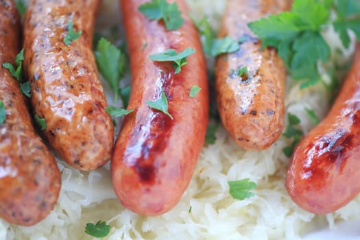 Cooked sausages on a bed of sauerkraut, sprinkled with cilantro