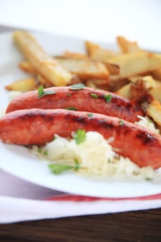 Platter of sausages on sauerkraut with fried potatoes