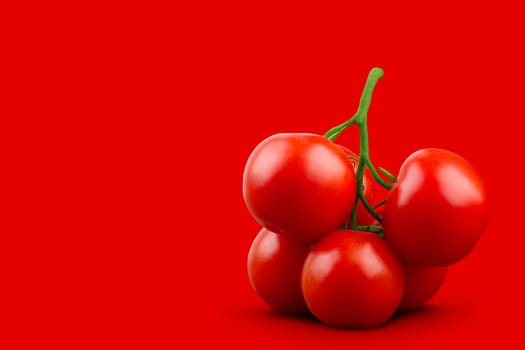 A bunch of tomatoes with green stem on red background. Horizontal, front view.