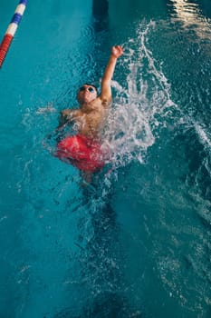Quadriplegic swimmer in the water. He is using the back stroke technique in the pool lane.