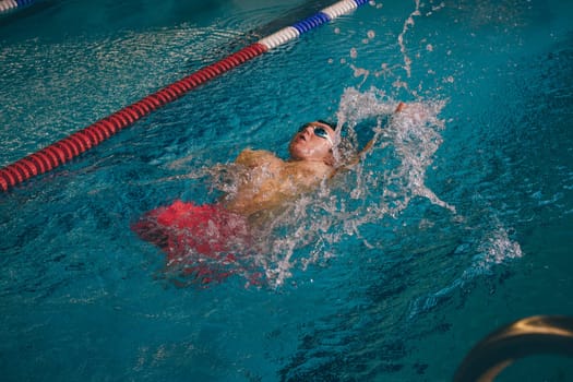 Quadriplegic swimmer in the water. He is using the back stroke technique in the pool lane.
