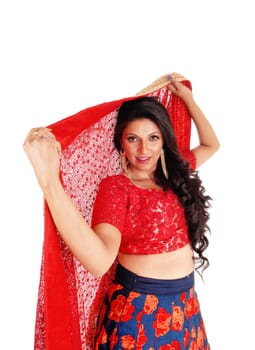 A very pretty woman in a red top and blue skirt holding a red scarf over.her head, isolated for white background..