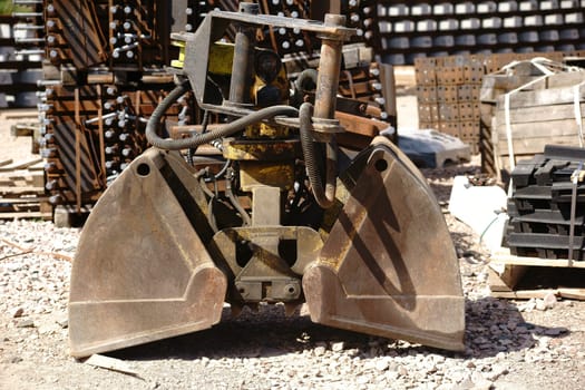 The close-up of an excavator shovel next to tools and materials.