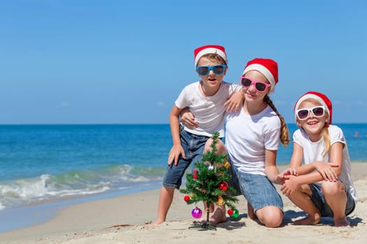 Three happy children  playing on the beach at the day time. Concept of Happy New Year.