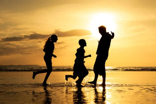 Father and children playing on the beach at the sunset time. Concept of friendly family.
