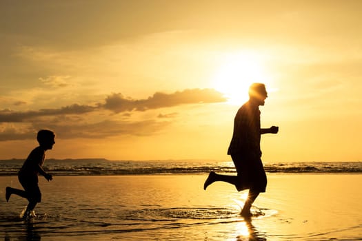 Father and son playing on the beach at the sunset time. Concept of friendly family.