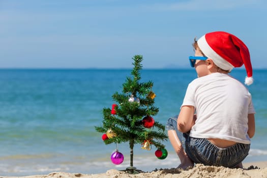 Happy little boy sitting on the beach at the day time. Concept of Happy New Year.