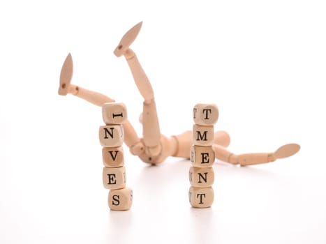 Financial risk concept with a fallen wooden puppet and dices with the word investment