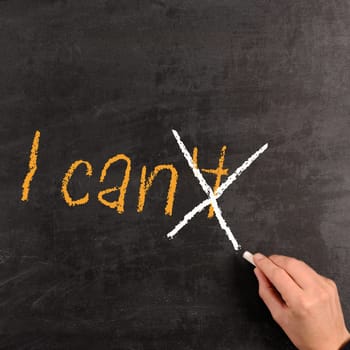 Hand writing with chalk on a blackboard the words "I can"""