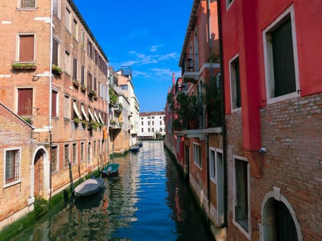 Classical picture of the venetian canals with boats across the canal.