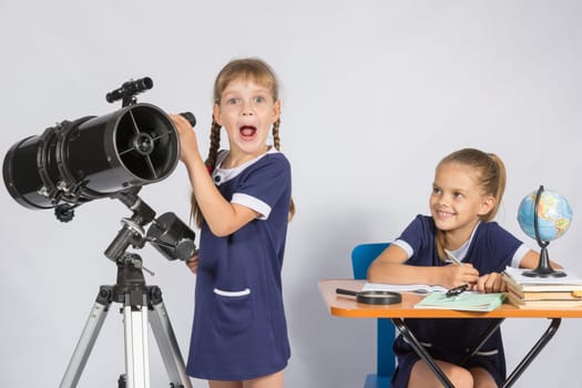 Girl surprised astronomer observing through a telescope, the other girl looked at her