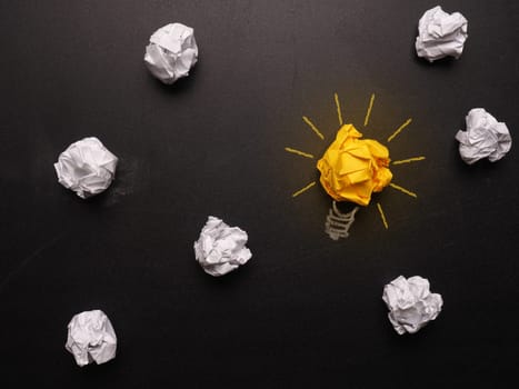 Crumpled paper on a chalkboard with a lightbulb
