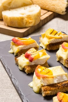 canapes, appetizer with grilled brie and nectarine plated on a slate dish